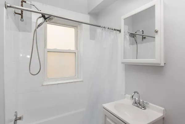 a bathroom with a sink a window and a shower
