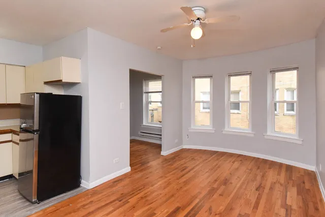 an empty room with wooden floor cabinet and windows