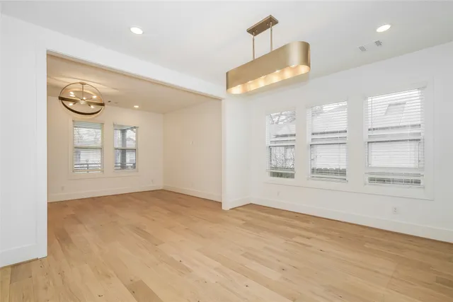 a view of an empty room with a window and hardwood floor