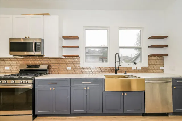 a kitchen with stainless steel appliances granite countertop a stove a sink and a microwave