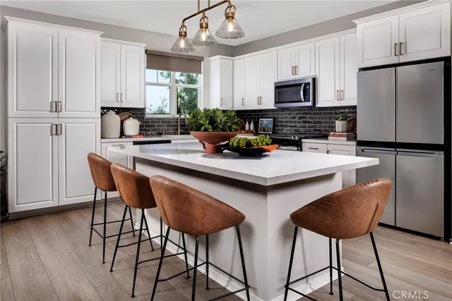 a kitchen with stainless steel appliances a dining table chairs refrigerator and sink