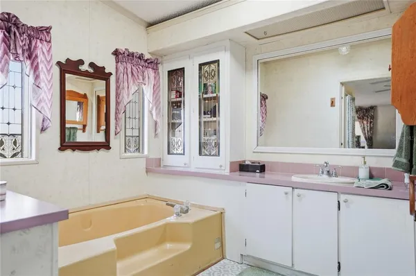 a bathroom with a tub sink and mirror