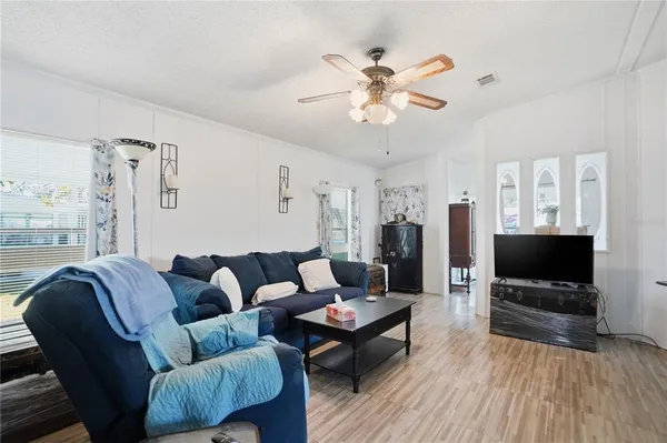 a living room with furniture a ceiling fan and a flat screen tv