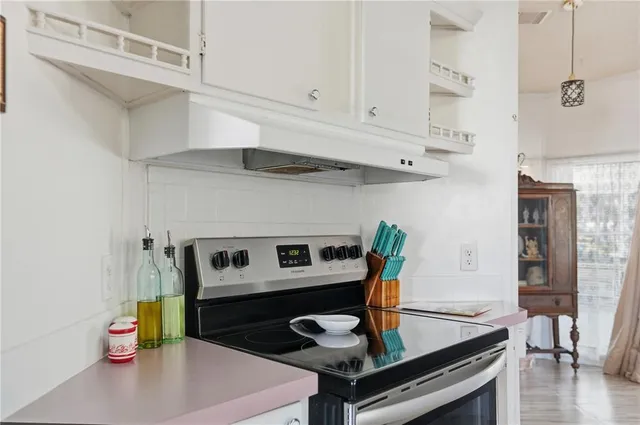 a kitchen with stainless steel appliances granite countertop a sink a stove and white cabinets