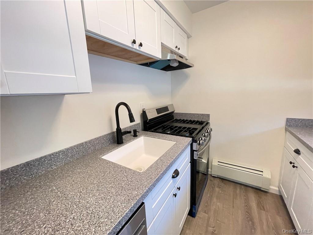 27 Tanager Road, Unit 2702 Monroe, NY 10950 - Photo 1 of 17 Kitchen featuring white shaker-style cabinetry, speckled countertops, a matte black gooseneck faucet, a stainless steel range, and wood-finish flooring