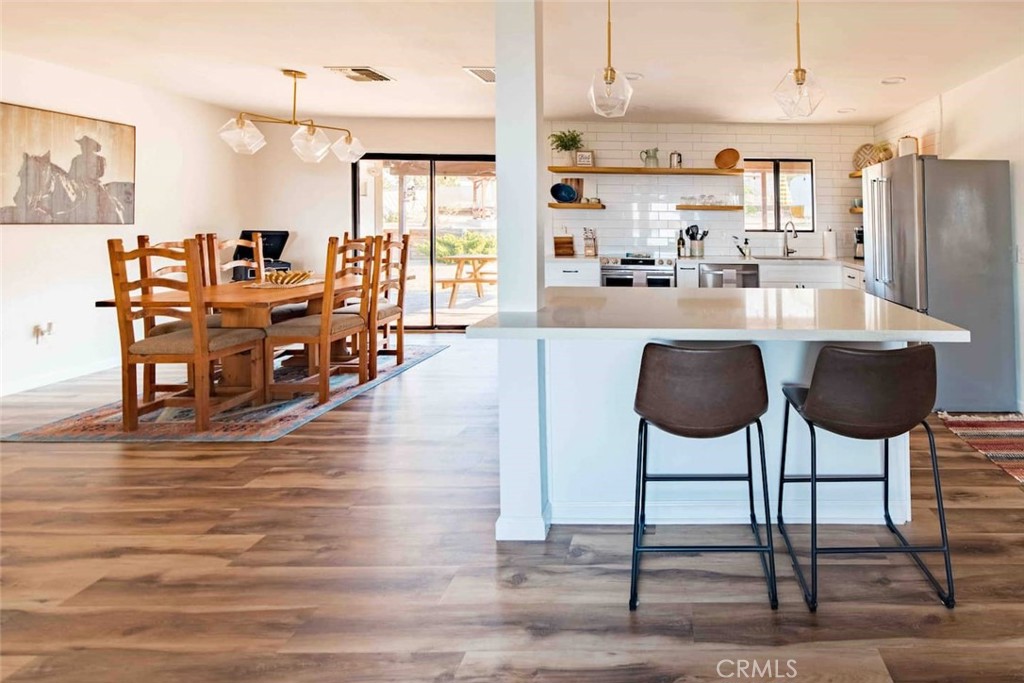 61029 Navajo Trail Joshua Tree, CA 92252 - Photo 14 of 41 a kitchen with stainless steel appliances kitchen island granite countertop a table chairs and a refrigerator