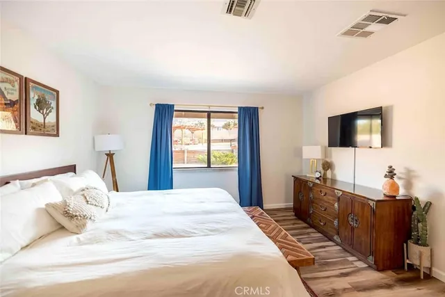 a bedroom with a large bed and a flat tv screen on dresser