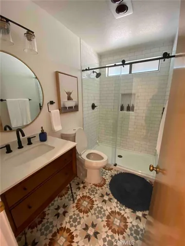 a bathroom with a granite countertop sink toilet a mirror a vanity and shower