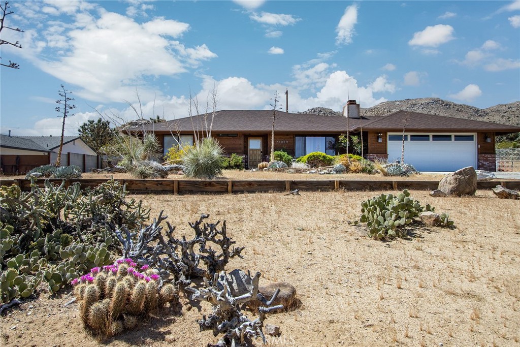 61029 Navajo Trail Joshua Tree, CA 92252 - Photo 9 of 41 a front view of a house with a yard and a lot of stuff