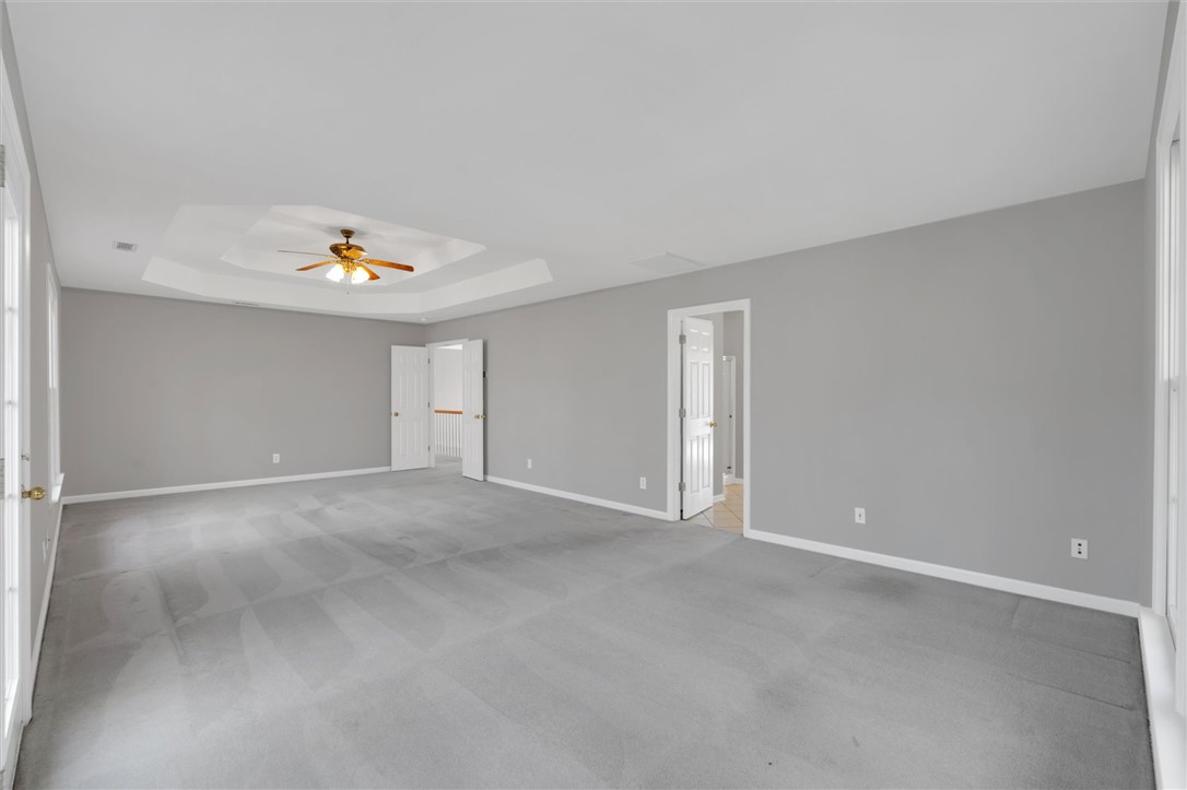 204 Red Maple Way Clemson, SC 29631 - Photo 26 of 48 This spacious primary bedroom features soft carpeting and a tray ceiling with a fan for comfort.
