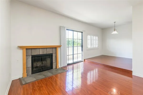 an empty room with wooden floor fireplace and windows