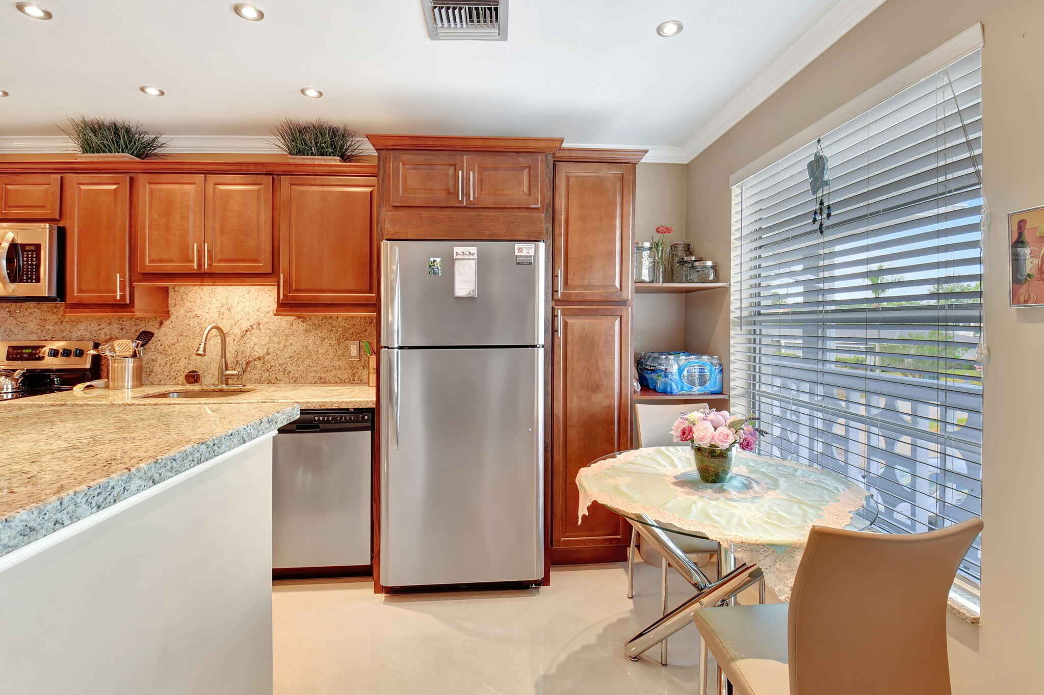 2721 Southwest 15th Street, Unit 203 Delray Beach, FL 33445 - Photo 8 of 55 a kitchen with stainless steel appliances granite countertop a refrigerator a sink a stove a dining table and chairs