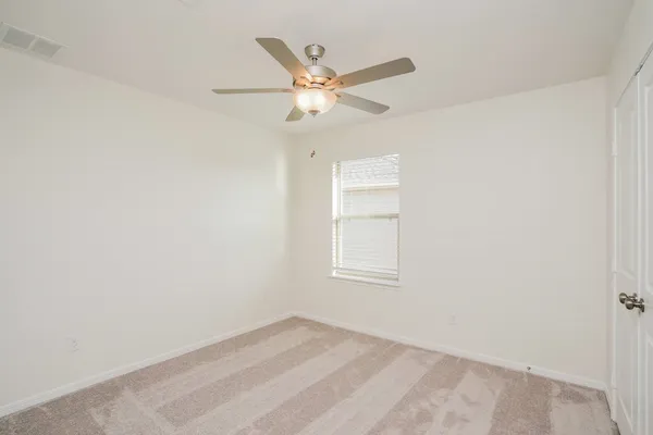 an empty room with a window and a fan