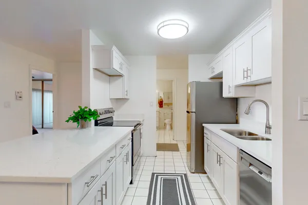 a kitchen with stainless steel appliances white cabinets and wooden floor