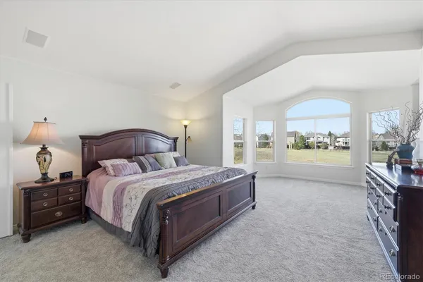 a spacious bedroom with a bed a couch and large window