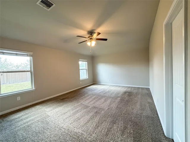 an empty room with windows and ceiling fan
