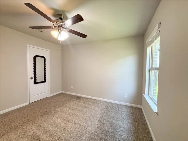 an empty room with windows and fan