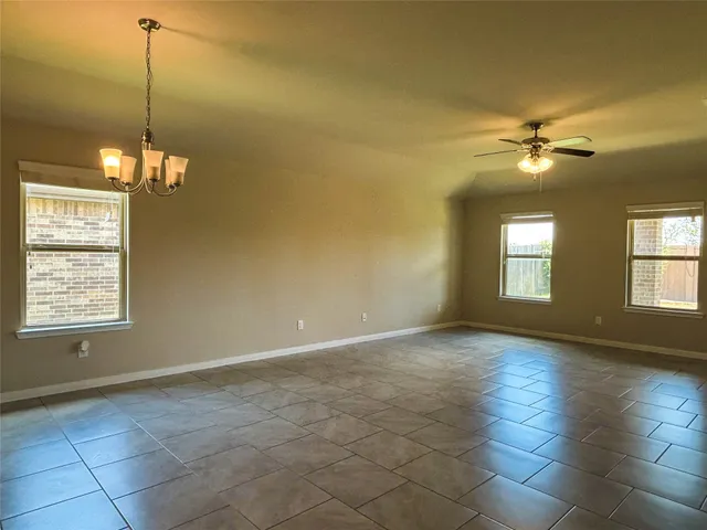 a view of an empty room with windows and chandelier fan