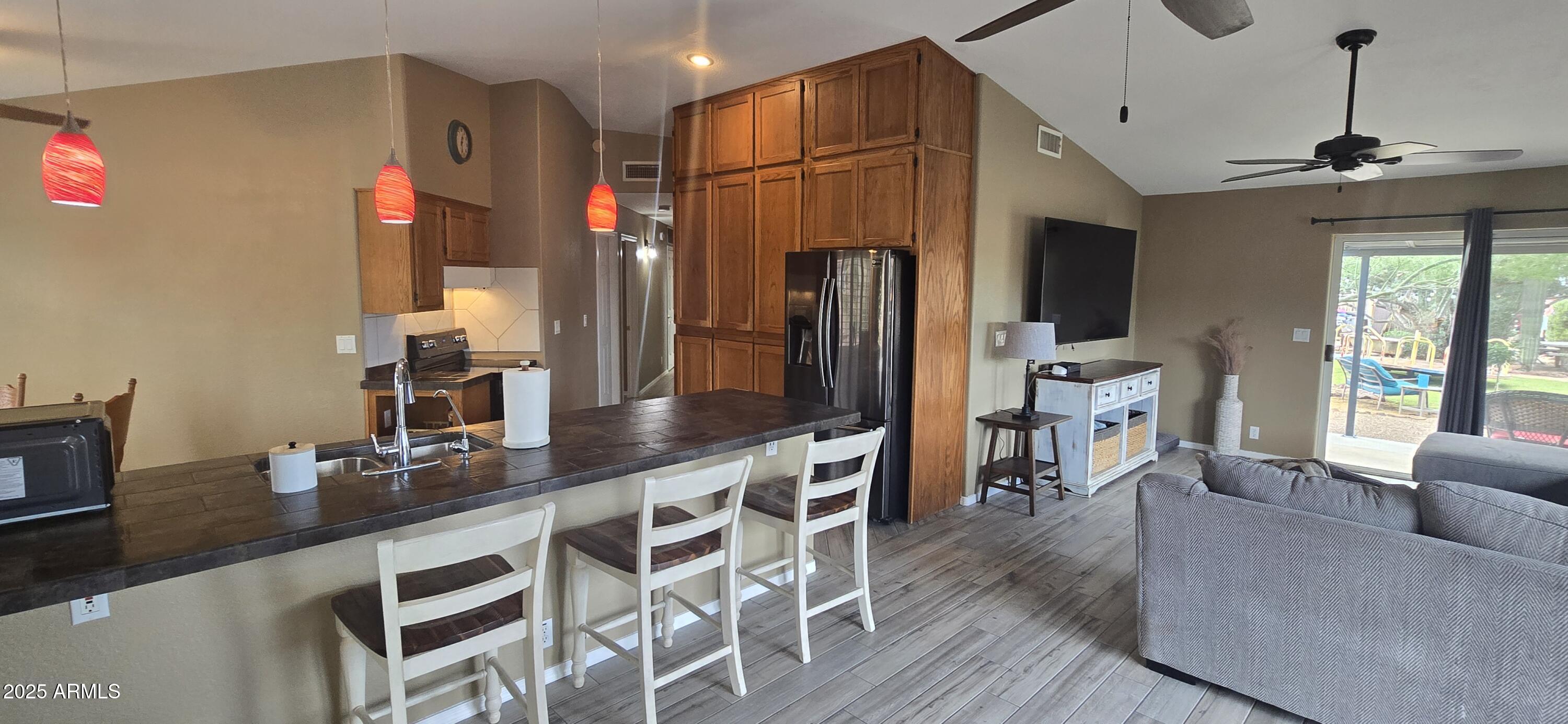 1502 South Prospectors Road Apache Junction, AZ 85119 - Photo 17 of 77 a kitchen with stainless steel appliances granite countertop a refrigerator a sink dishwasher a dining table and chairs with wooden floor