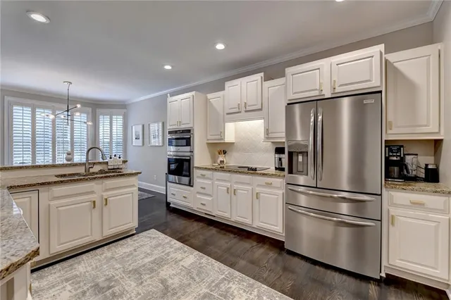 a kitchen with stainless steel appliances granite countertop a refrigerator sink and white cabinets