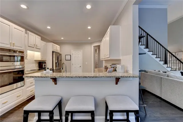a kitchen with stainless steel appliances granite countertop a white cabinets and chairs