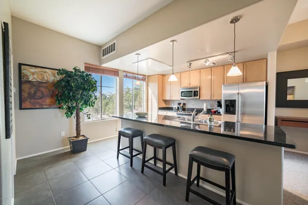 a kitchen with stainless steel appliances a table and chairs in it