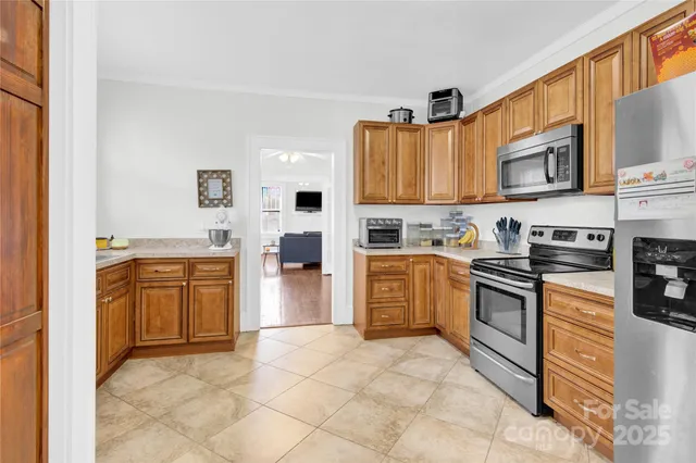 a kitchen with stainless steel appliances granite countertop a stove top oven a sink a refrigerator and white cabinets