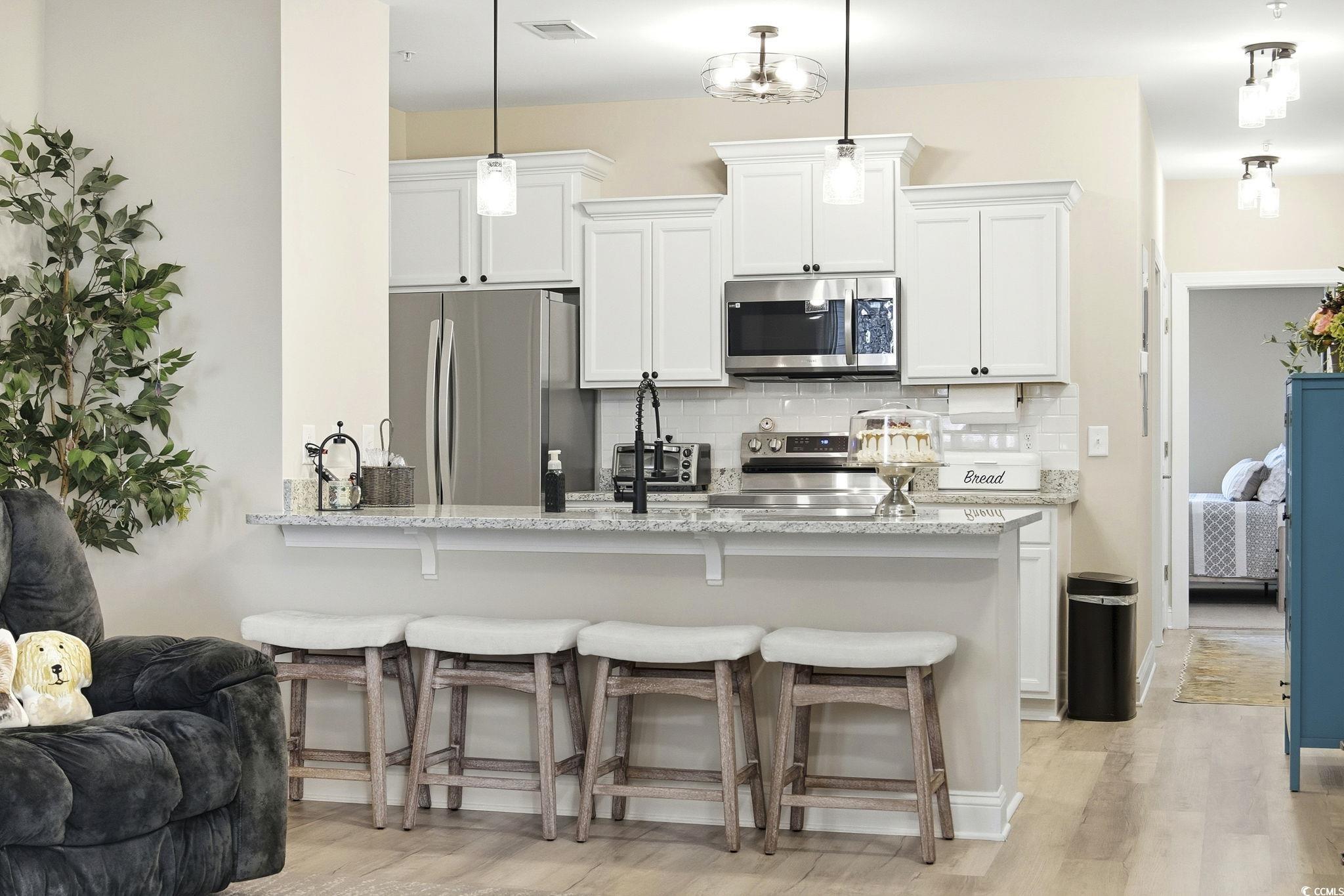 165 Ella Kinley Circle, Unit 302 Myrtle Beach, SC 29588 - Photo 8 of 38 Kitchen featuring a breakfast bar area, stainless steel appliances, white cabinets, and a peninsula