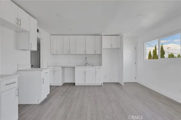 a kitchen with white cabinets and wooden floor