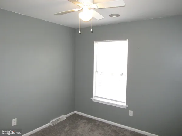 an empty room with a window and a fan