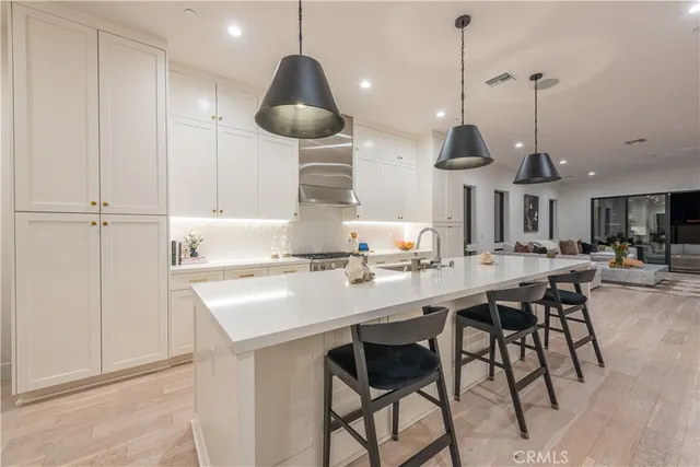 a kitchen with stainless steel appliances a dining table chairs and white cabinets