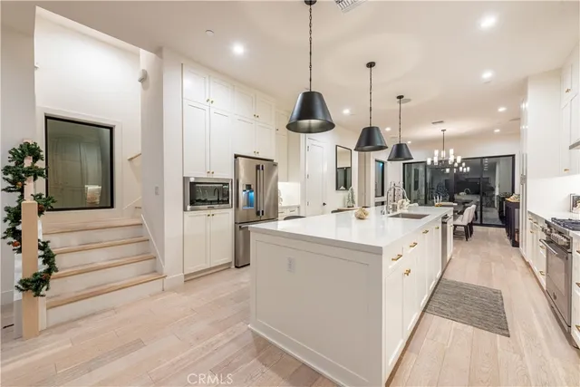 a large kitchen with stainless steel appliances kitchen island a large counter space a sink and a wooden floors
