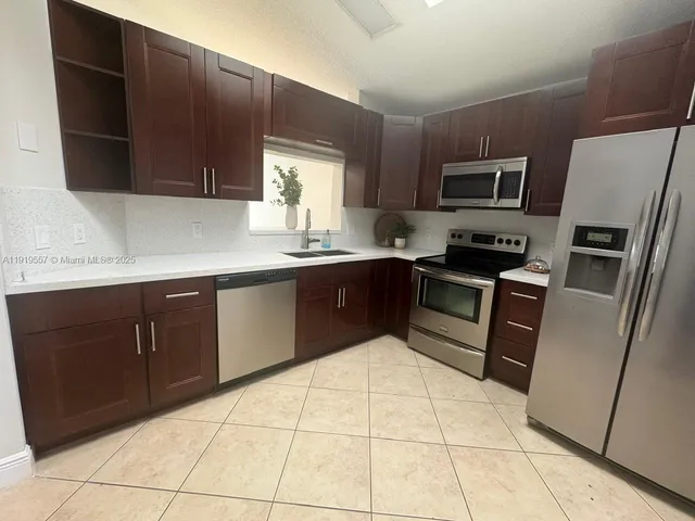 a kitchen with stainless steel appliances granite countertop a refrigerator and a stove top oven