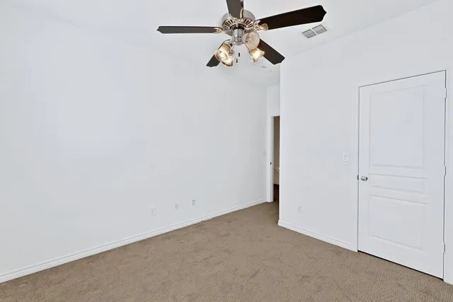 an empty room with a fan & a ceiling fan