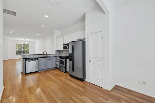 a large kitchen with a wooden floor and a refrigerator