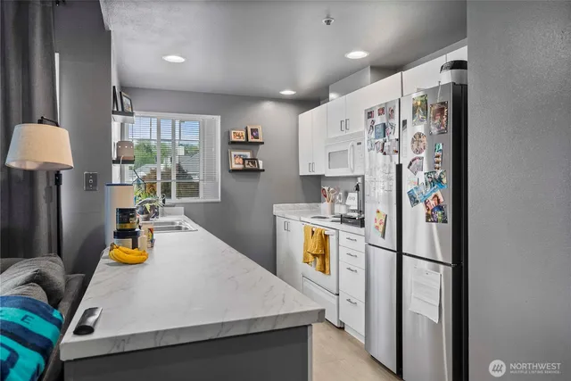 a kitchen with stainless steel appliances a refrigerator a sink dishwasher a stove a dining table and chairs with wooden floor