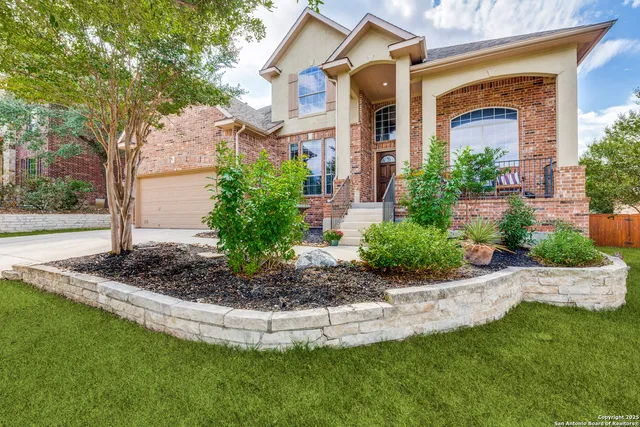 a view of a house with a small yard plants and a large tree