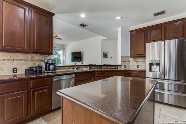 a kitchen with stainless steel appliances granite countertop a sink a stove and a refrigerator