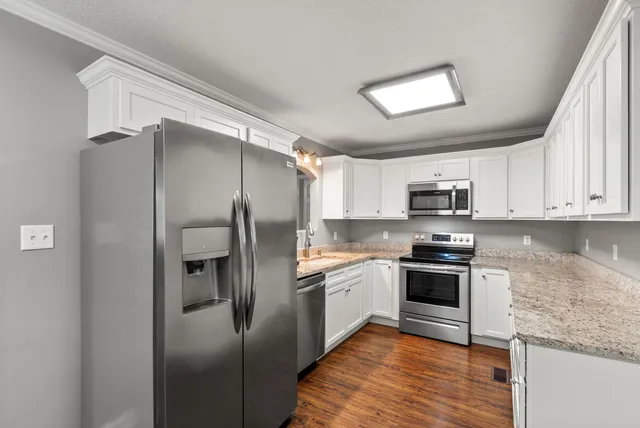 a kitchen with stainless steel appliances granite countertop a refrigerator stove and sink
