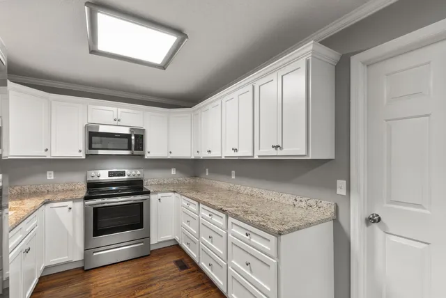 a kitchen with stainless steel appliances granite countertop a stove a sink and a microwave