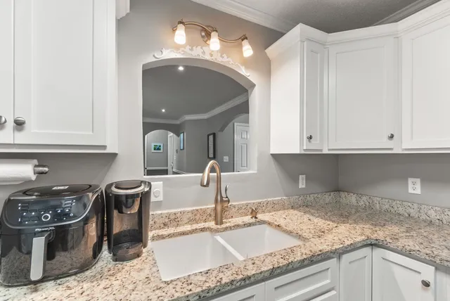 a kitchen with granite countertop a sink a stove and cabinets