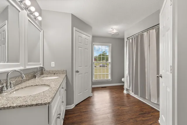 a bathroom with a granite countertop sink a mirror and a shower