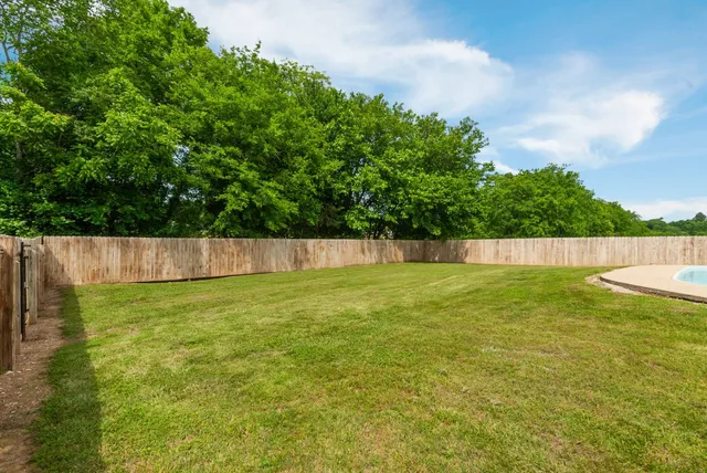 a view of yard with swimming pool and trees in the background