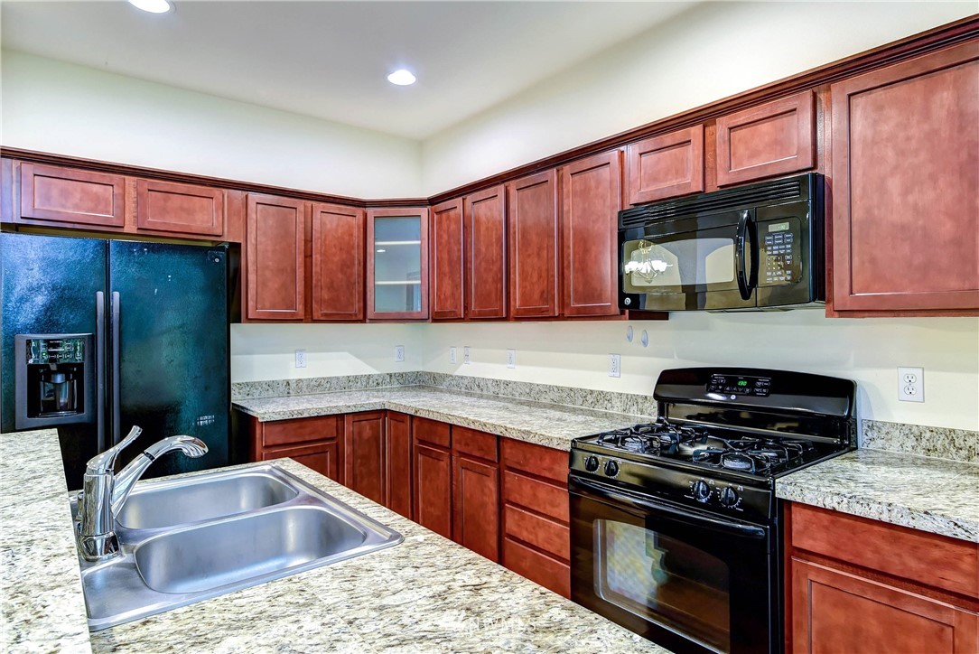 1031 215th Place Southeast Bothell, WA 98021 - Photo 11 of 25 a kitchen with granite countertop a sink stove and cabinets