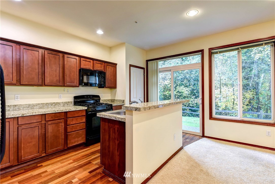 1031 215th Place Southeast Bothell, WA 98021 - Photo 9 of 25 a kitchen with stainless steel appliances granite countertop wooden cabinets a stove a sink and a large window