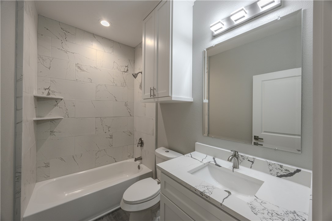 729 Ebenezer Lane Brenham, TX 77833 - Photo 21 of 25 a bathroom with a granite countertop sink toilet mirror and bathtub