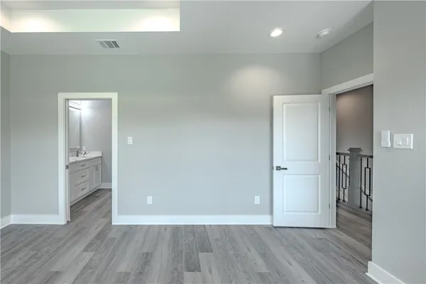 a view of an empty room with wooden floor and a bathroom