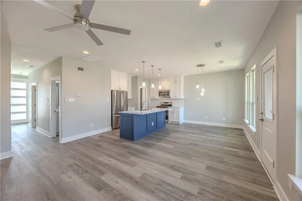 a view of kitchen and empty room with wooden floor