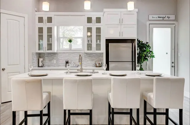 a kitchen with stainless steel appliances granite countertop a dining table chairs and a refrigerator