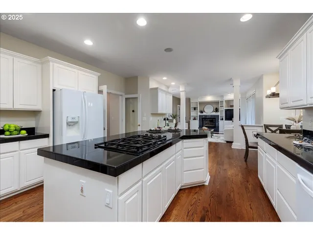 a kitchen with stainless steel appliances granite countertop a stove a sink a refrigerator and white cabinets